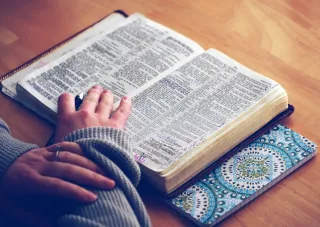 A woman reading a dictionary at a table.